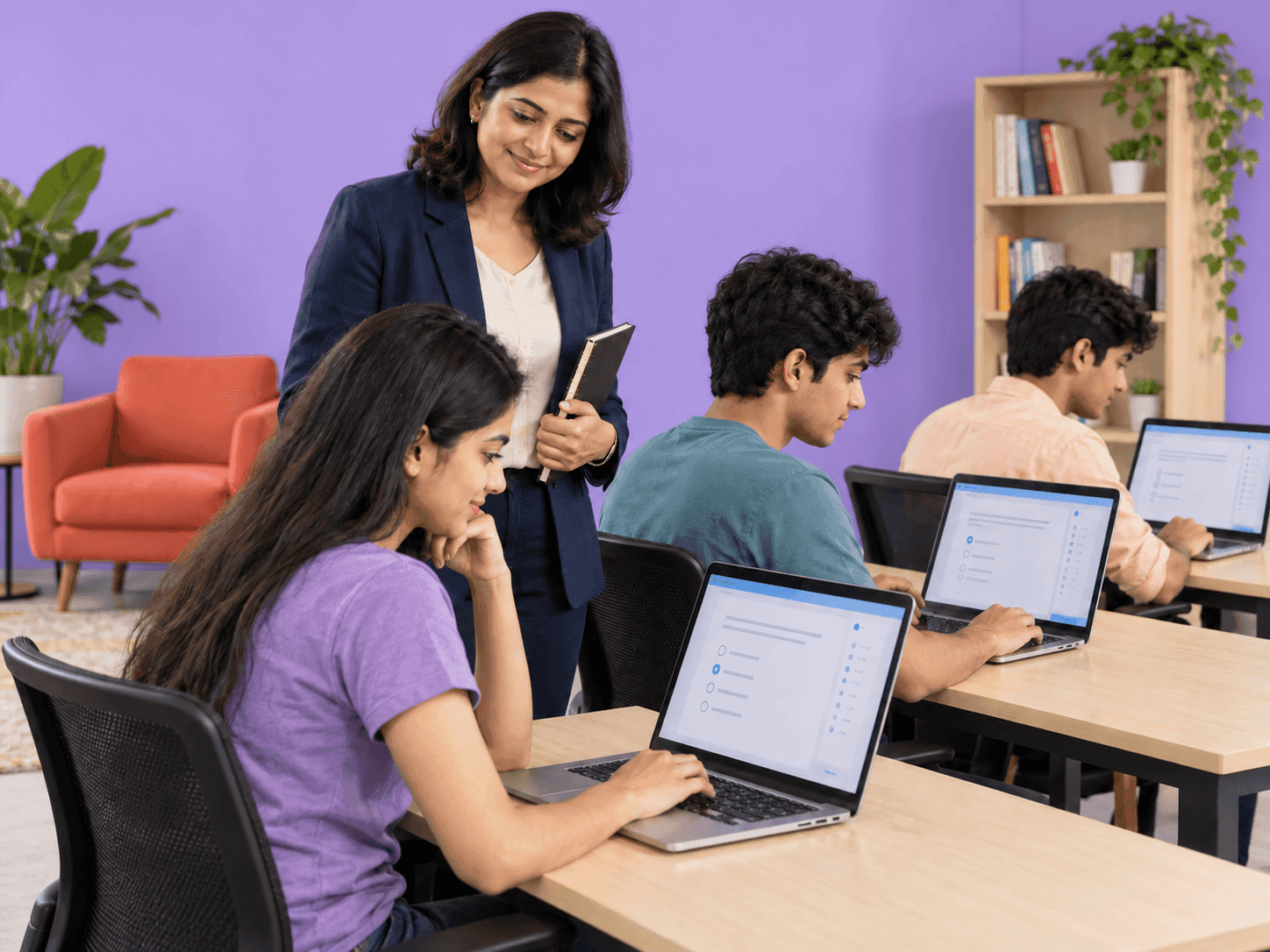 Teacher guiding students working on laptops